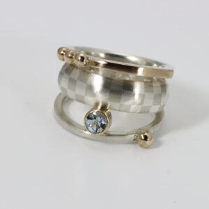 Ring with an aquamarine and a checkerboard pattern. Three connected bands.