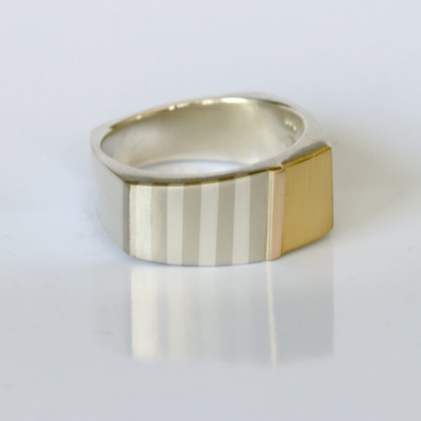 Contemporary mens ring fabricated in sterling silver,22k, and 14k gold. The ring has subtle striped pattern.