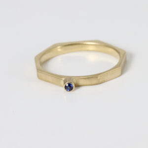 A narrow octagon shaped ring in 14k yellow gold with a bezel set sapphire.