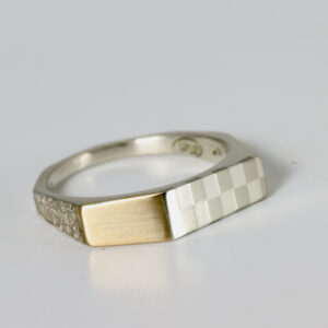Checkerboard mixed metal ring. Fabricated in sterling silver and 18k. The ring has some texture and a geometric shape.