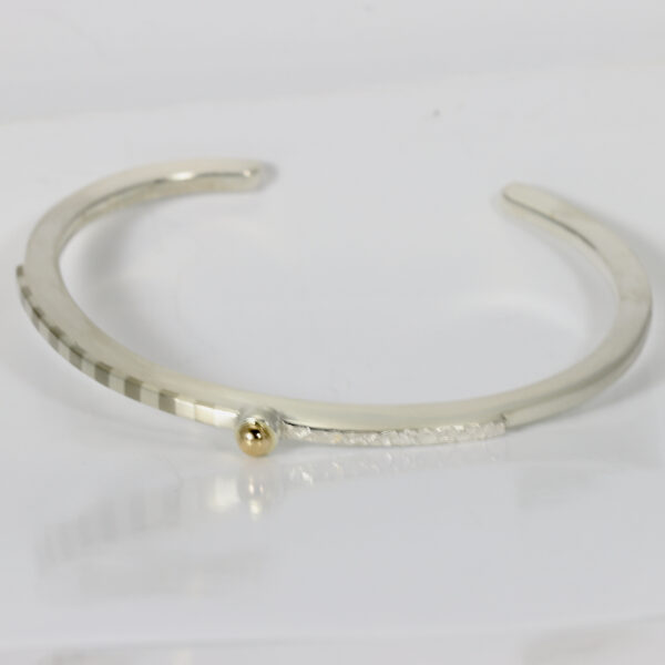Sterling silver cuff bracelet with texture, a striped pattern and a 14k gold ball.