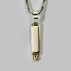 Mixed metal Pendant. Fabricated in sterling silver and 14k gold. A vertically hanging rectangular shape with a gold ball at the bottom.