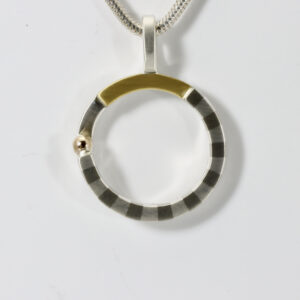 Mixed-metal circular pendant. Hand-fabricated in sterling silver, 22k, and 14k gold. The striped pattern is subtle and adds detail to the circular pendant.