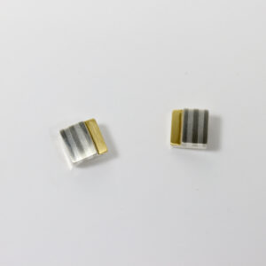Mixed metal stud earring with a striped pattern and 22k. The earring is square in shape.