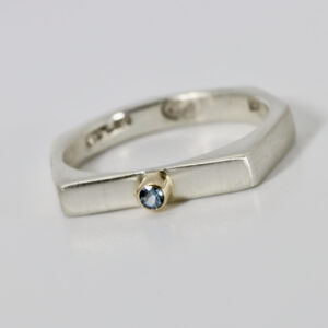 Stackable ring with five side fabricated in sterling silver with an aquamarine set in a 14k yellow gold bezel.
