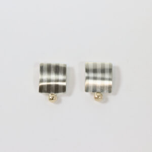 A square earring with a striped pattern and a gold ball of the bottom.