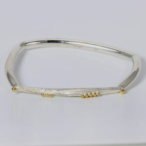 A squarish shaped sterling silver bracelet with texture and 14k gold balls,