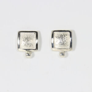 A textured square post earring with a ball at the bottom. Fabricated in sterling silver