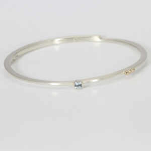 Sterling silver oval shaped bangle with three little 14k gold balls and an Aquamarine gemstone.