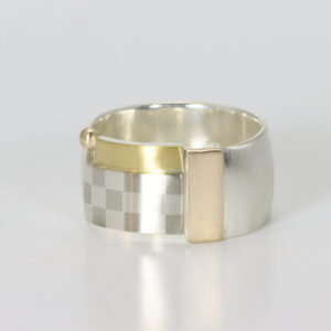 A wide sterling silver band with a checkerboard pattern, 14k, and 22k gold.