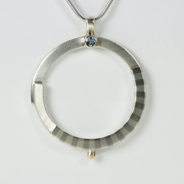 Round Open Pendant with an Aquamarine and a striped pattern.