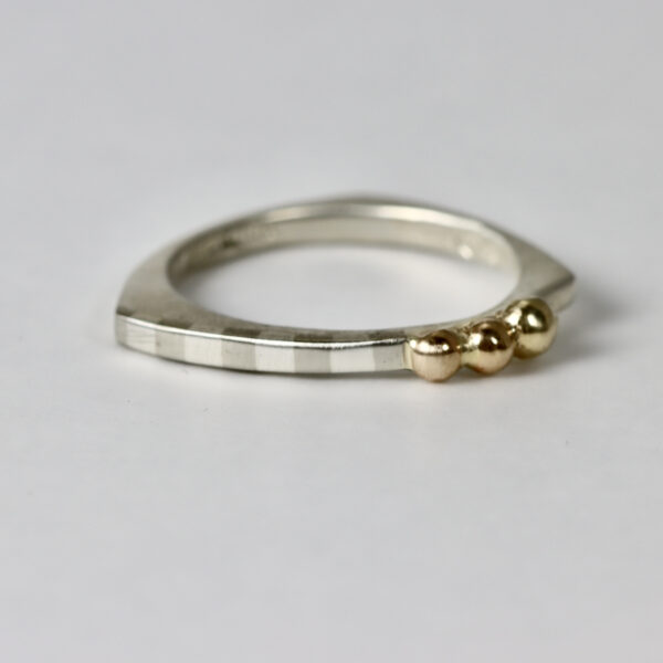 Contemporary shaped striped narrow ring in sterling silver with three 14k gold balls.