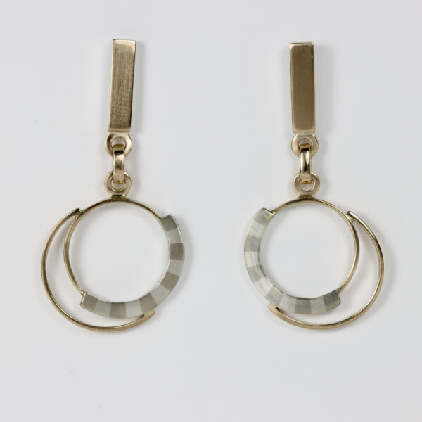 Mixed metal earrings with a striped pattern and dangling circles. Hand fabricated in sterling silver and 14k gold.