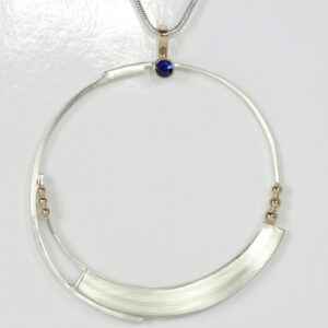Delicate circular pendant with a sapphire. Details include a subtle striped pattern and solid 14k gold balls.