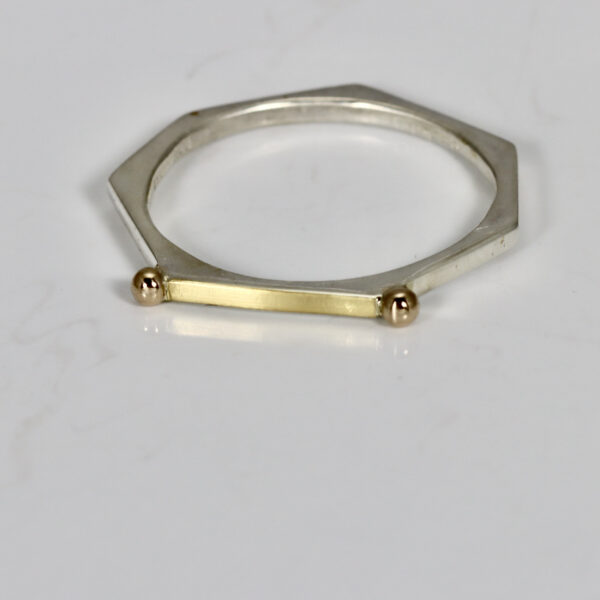 Narrow stacking ring fabricated in sterling silver, 22k, and 14k. The ring is heptagon shaped.