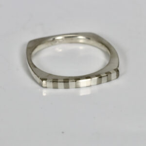 Striped stacking ring fabricated in sterling silver. The ring is squarish in shape and has a subtle striped pattern.