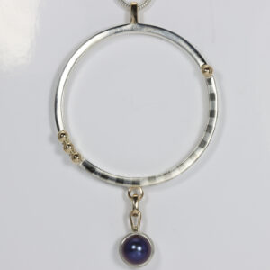 Open Circular Pendant with a subtle striped pattern and a dangling black pearl. Hand fabricated in sterling silver and 14k gold.