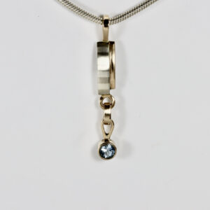 Mixed-metal Pendant with a dangling Aquamarine faceted gemstone.