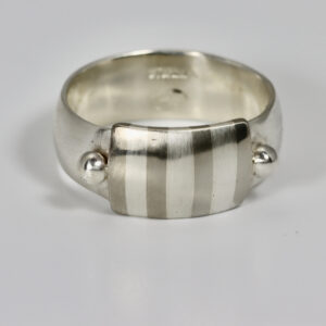 A wide sterling silver band with a subtle striped pattern and two sterling balls.