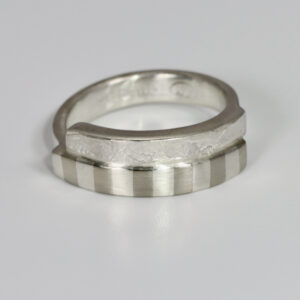 A sterling silver ring with texture and a subtle striped pattern.