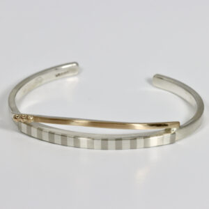 A cuff bracelet with a subtle hand-fabricated striped pattern contrasting with 14k gold. Details include little 14k balls.