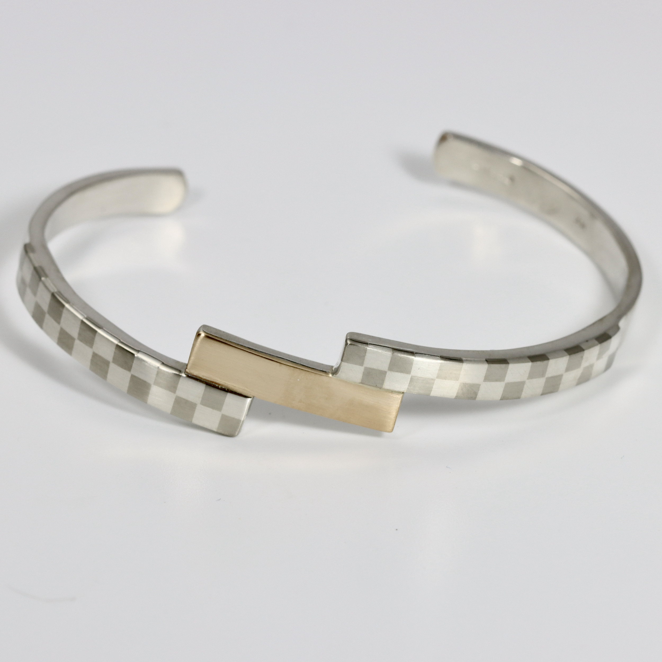 Tiered checkerboard cuff bracelet. Hand-fabricated in sterling silver and 14k gold. The gold is centered between two checkerboard patterns.