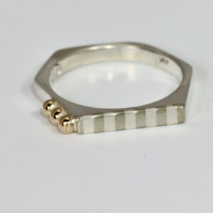 Narrow hexagon shaped ring with a subtle striped pattern and three solid 14k balls.