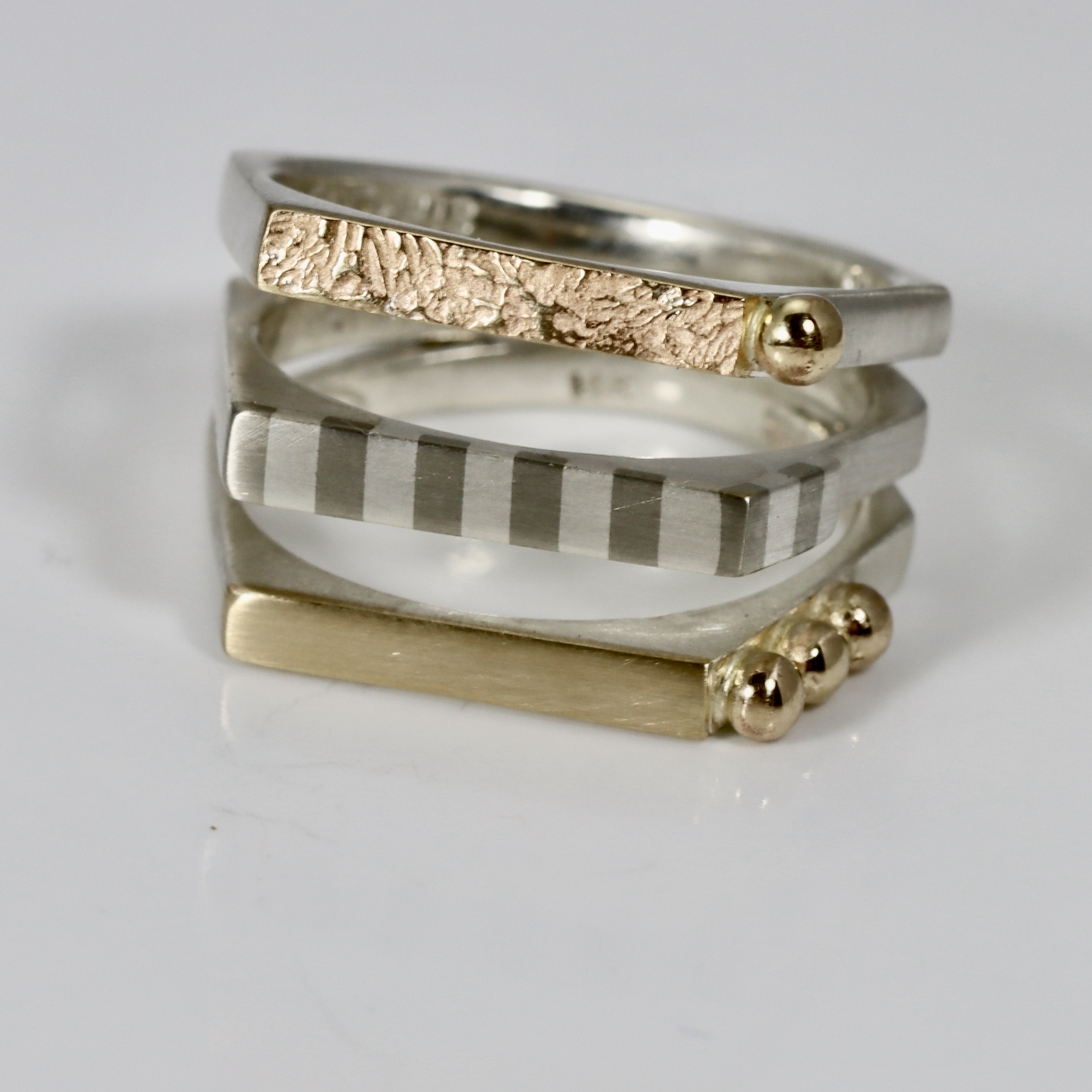Triple band modern ring. Hand-fabricated in sterling silver, 14k textured and smooth gold. Details include a subtle striped pattern and solid 14k gold balls.