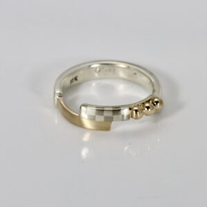 A hand-fabricated sterling silver and gold mixed metal ring featuring a checkerboard pattern accented with small 14k gold balls.