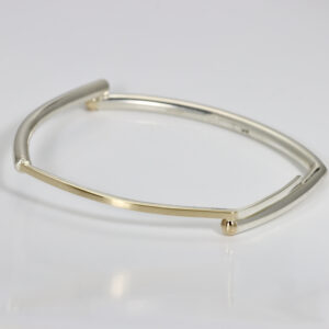 A geometric two-tone rectangular wrist bangle made from sterling silver, accented with a contrasting 14k yellow gold. The bracelet has a lovely Matte finish.
