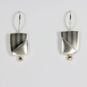 A pair of handmade mixed-metal drop earrings utilizing the marriage of metals technique. The flat, geometric handcrafted earrings are composed of alternating horizontal stripes. The earrings hang from sterling silver French hooks. A 14k gold ball contrast with the matte finished sterling silver.