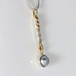 Grey pearl mixed metals pendant. Hand fabricated in sterling silver and 14k gold. Featuring a subtle striped pattern.