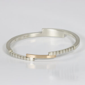 Mixed metals modern bangle with a striped pattern. Hand fabricated in sterling silver and 14k gold.