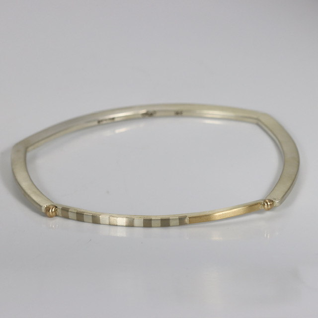 Narrow minimalist bangle bracelet featuring marriage of metals striped pattern, contrasted against polished 14k yellow.