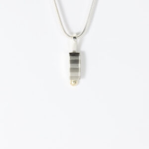 The perfect daily minimalist piece. The vertically striped silver pendant, finished with a subtle 14k gold ball accent.