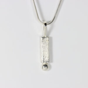 A textured sterling pendant with a smooth shinny ball centered on the base.